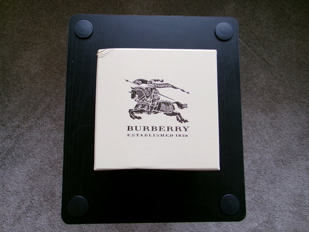 Burberry product on a black stand with a gray background
