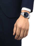Hand wearing a silver watch with a dark face on a white background